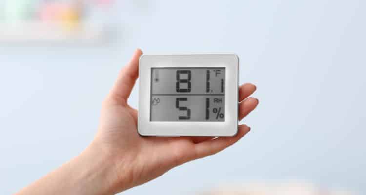 Person checking indoor humidity levels with digital meter in Annapolis home