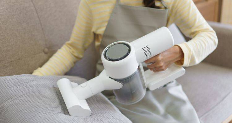 Handheld vacuum cleaning crumbs from sofa