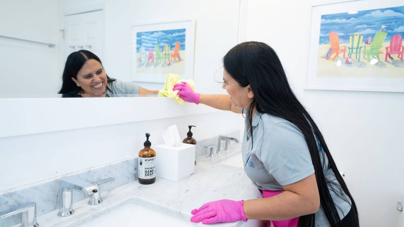 Professional cleaner doing detailed bathroom and kitchen cleaning during weekly service