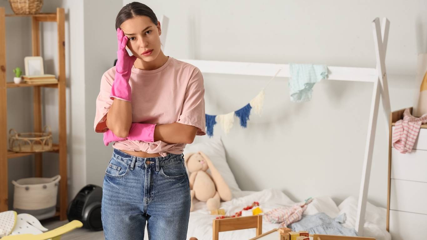 Person holding their head while looking at cluttered shelves